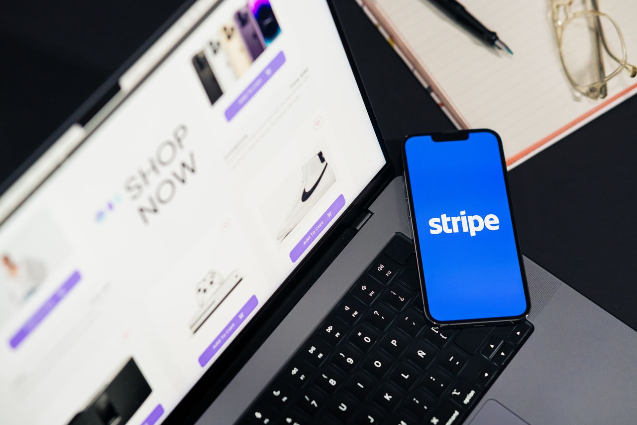services-04 Mobile phone displaying Stripe app on a laptop with an eCommerce site open, symbolizing online shopping.